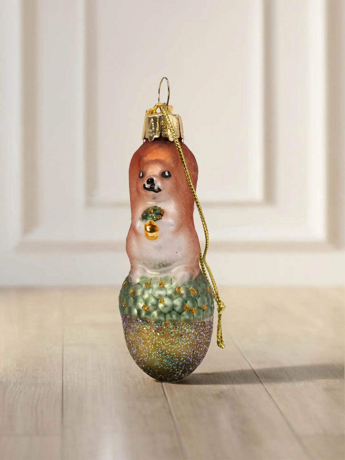 Glasornament Eichhörnchen klein: braun-beiges Eichhörnchen sitzend auf grüner Eichel mit Goldglitter-Akzenten, goldenes Hängeelement