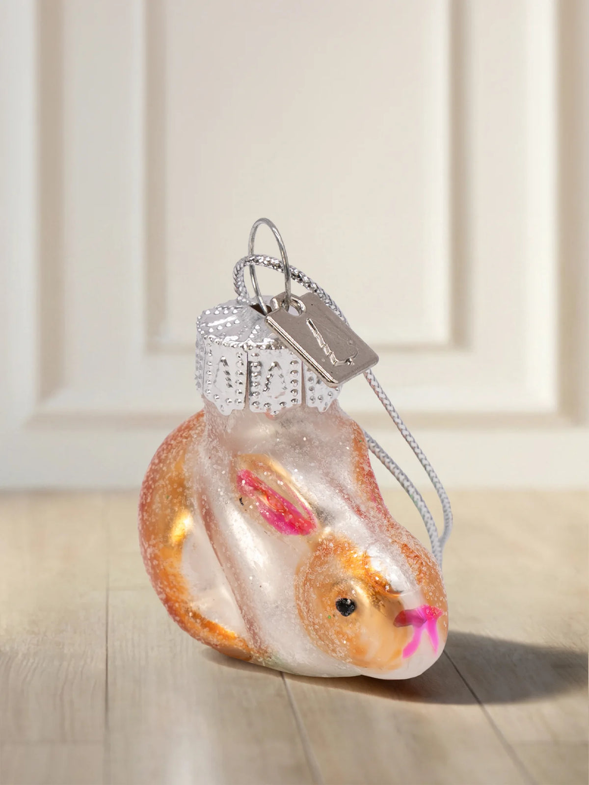 Glasornament Hase: zusammengerollter Hase in Weiß-Irisierend mit Orangetönen, pinke Ohren und Wangen, Glitter-Finish, silbernes Hängeelement