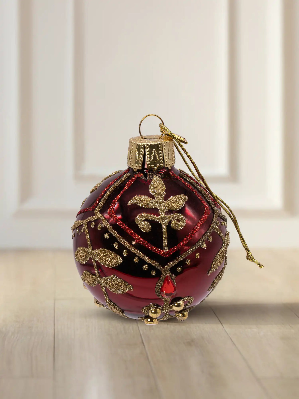 Glaskugel Bordeaux glanz 6cm: bordeauxrote Glaskugel mit Glanzfinish, aufwendiges goldenes Dekor aus Perlen und Straßsteinen, florales Muster mit rotem Glitter, goldener Aufhänger mit goldener Kordel