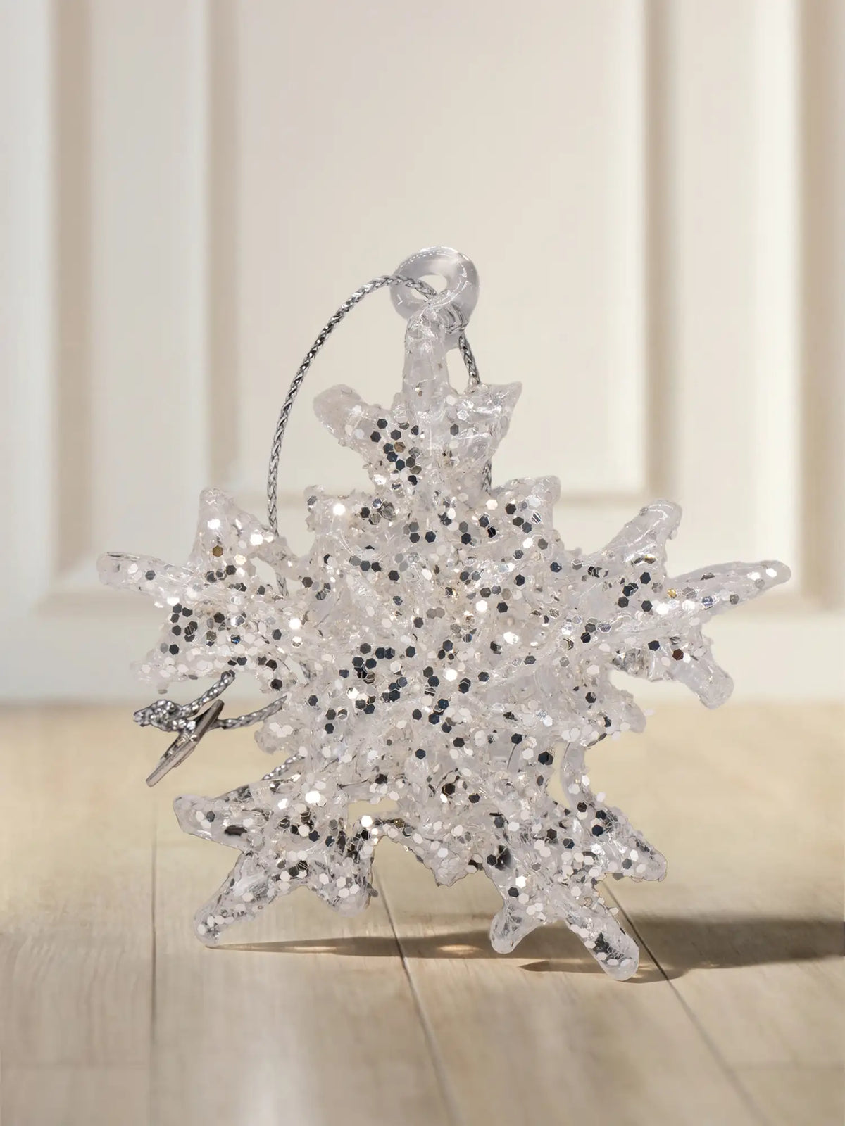 Glasornament Schneeflocke mit Glitzer: Transparente Schneeflocke mit sechszackiger Struktur und silbernem Glitzerbesatz, kleiner silberner Anhänger an einem Zacken, silbernes Aufhängeband