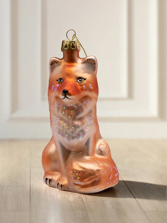 Glasornament Fuchs: sitzender Fuchs in Orange und Creme mit schillernden Glitzerakzenten an Wangen, Brust und Schwanz, goldene Aufhängekappe