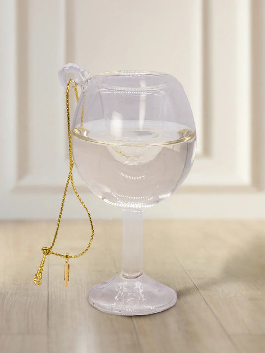 Gläsernes Ornament in Form eines Glases mit klarer Flüssigkeit, vermutlich Gin Tonic oder Wasser, mit Goldkordel und kleinem Metallanhänger.