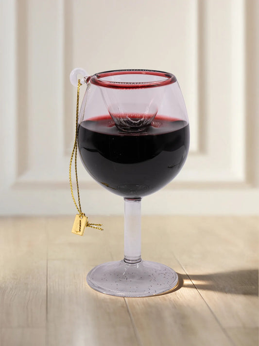 Gläsernes Ornament in Form eines Rotweinglases, gefüllt mit dunkelrotem Wein, rotem Rand und goldener Aufhängekordel mit kleinem Metallanhänger.