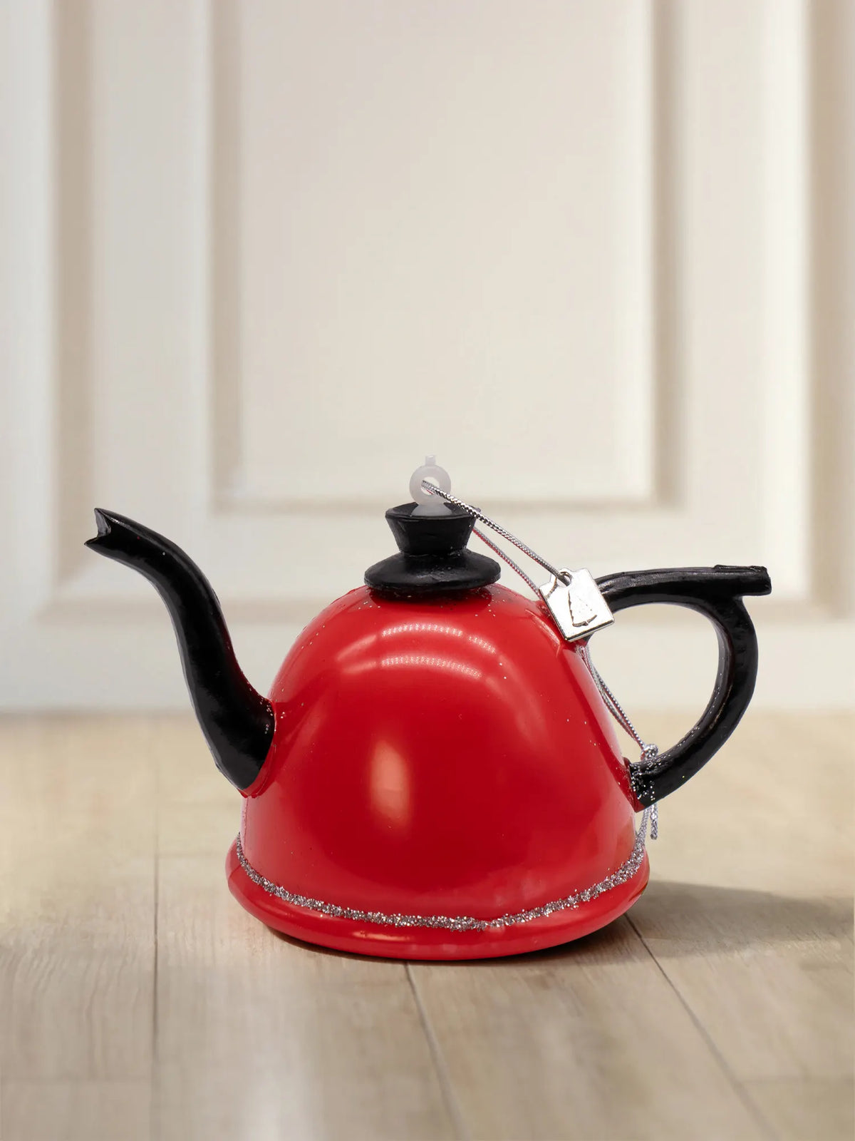 Glazen theepotornament: rode theepot met zwart handvat, schenktuit en dekselknop, zilveren glitterrand en zilveren koord