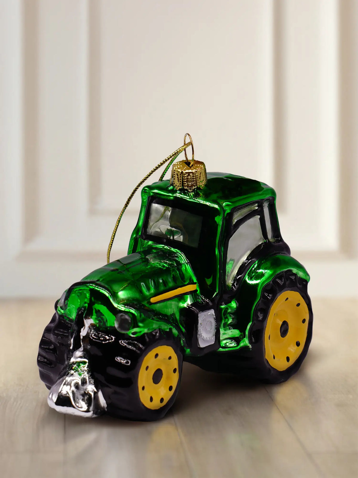 Glasornament Traktor: grüner Glastraktor mit gelben Rädern, silbernem Frontgerät und schwarzen Details, goldener Aufhänger mit goldener Kordel