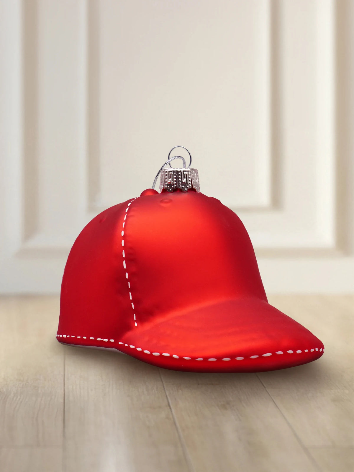 Glasornament Golfcap: rote matte Glasfigur einer Golfcap mit weißen Nähten, silberner Aufhänger mit silberner Kordel