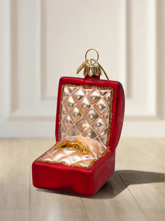 Rotes, mattes Glasornament in Form einer geöffneten Ringschatulle mit goldgesteppter Polsterung, goldenem Ring mit Stein und Goldglitzerrand.
