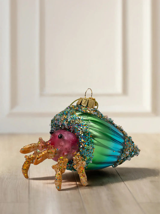 Glasornament Krabbe in Muschel: Pinke Krabbe mit orangefarbenen Beinen und Glitzer, grün-türkises Schneckenhaus mit buntem Glitzerbesatz am Rand, goldene Aufhängekappe