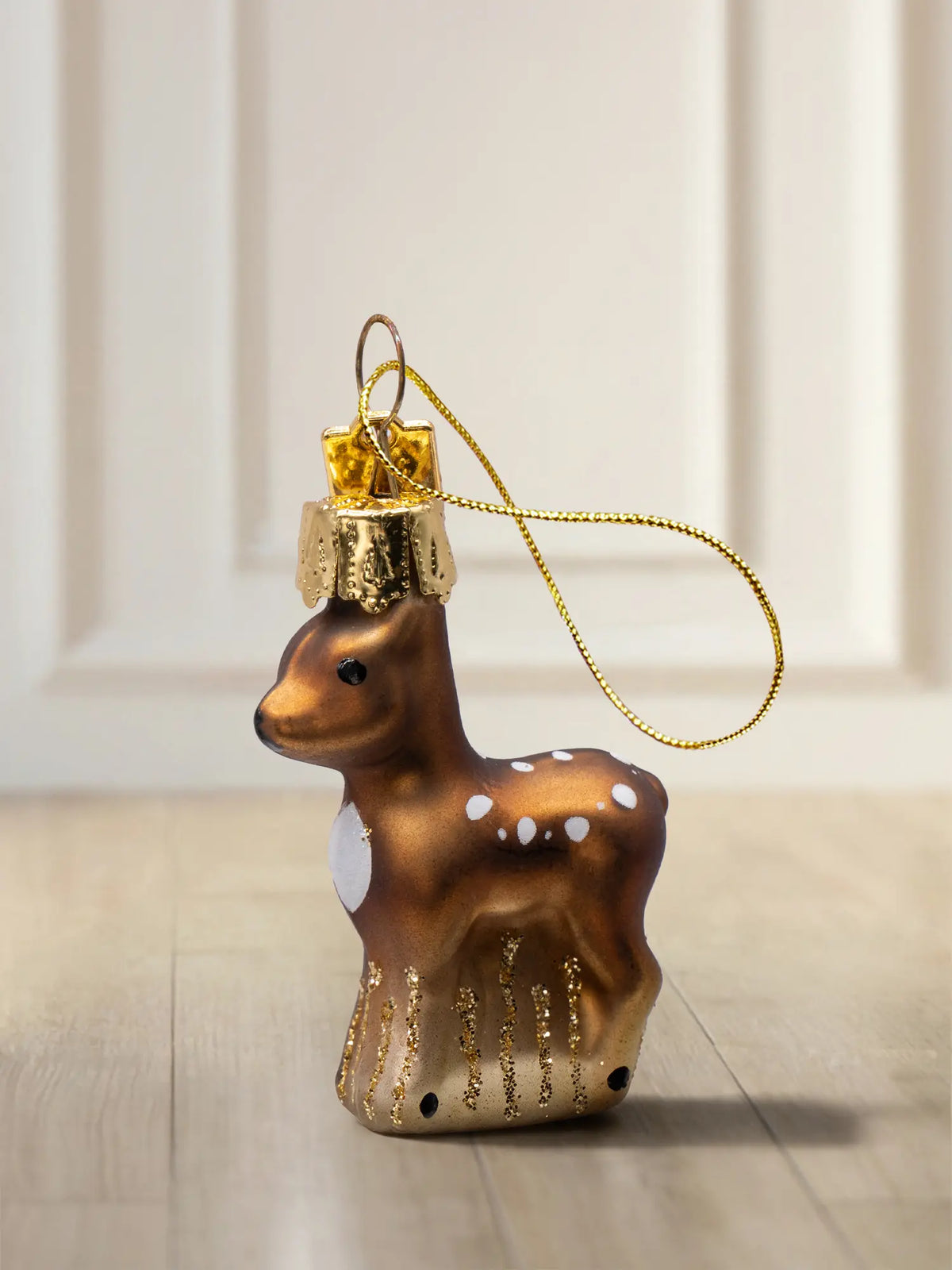 Glasornament Rehkitz: braunes Rehkitz mit weißen Tupfen und goldenen Glitter-Strichen am Bauch, goldenes Hängeelement