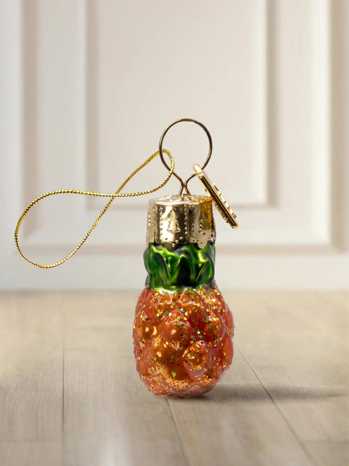 Glasornament Ananas: orange-rote Ananas mit grünem Blätterkopf und Goldglitter-Finish, goldenes Hängeelement