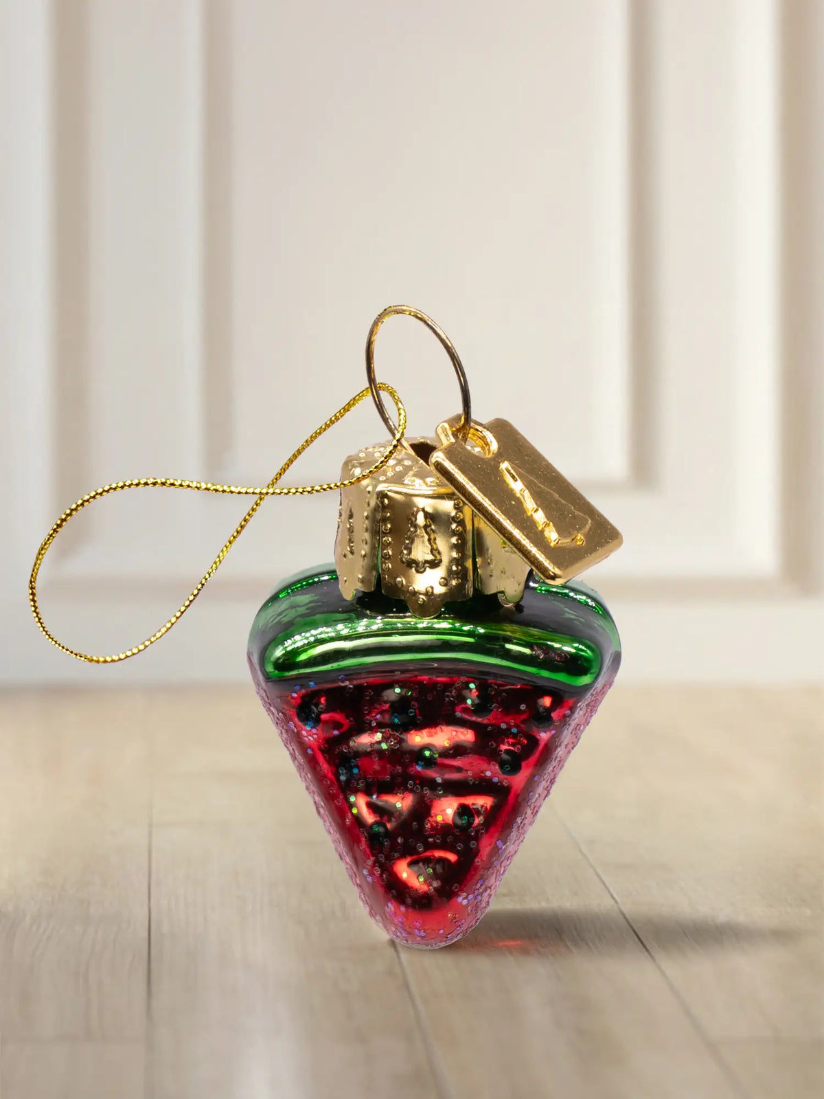 Glasornament Wassermelone: dreieckige Wassermelonenscheibe mit grüner Schale, rotem Inneren und Glitter-Kernen, goldenes Hängeelement