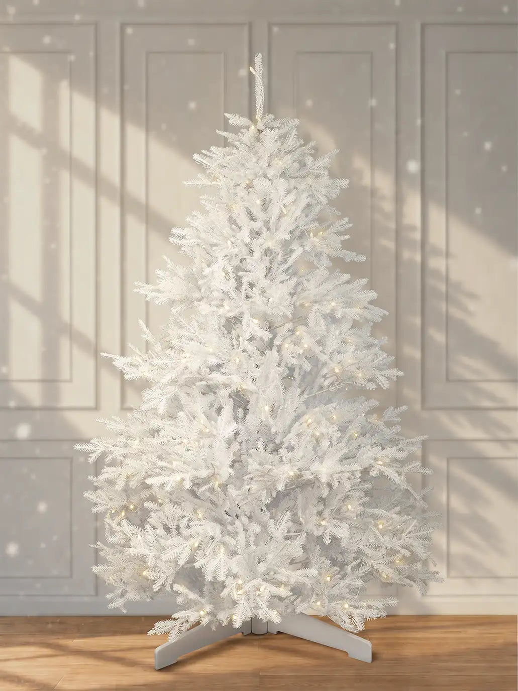 Weißer künstlicher Weihnachtsbaum in 180 cm mit warmweißer LED-Beleuchtung und weißem Standfuß vor heller Wand.