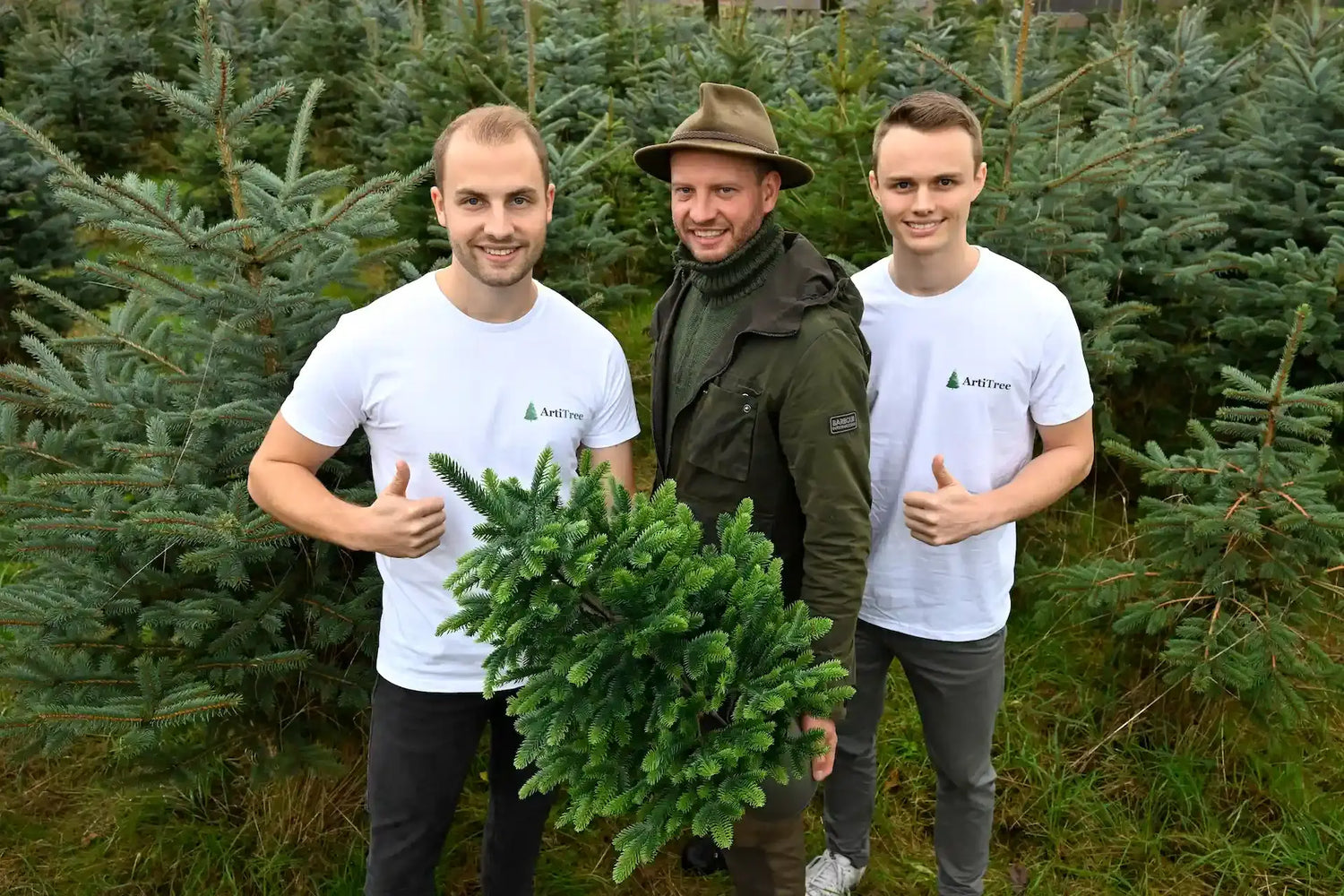 Drei Gründer mit einem künstlichen Weihnachtsbaum